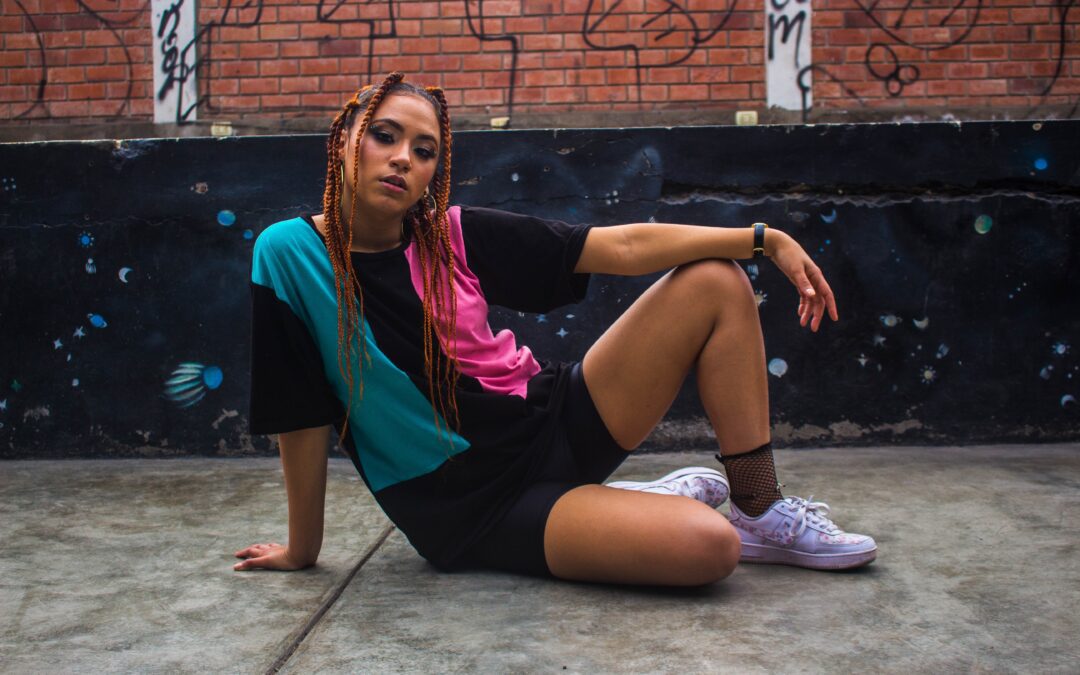 Choosing the Best Location for Streetwear Pictures. Woman sitting on sidewalk with graffiti on the wall behind her.